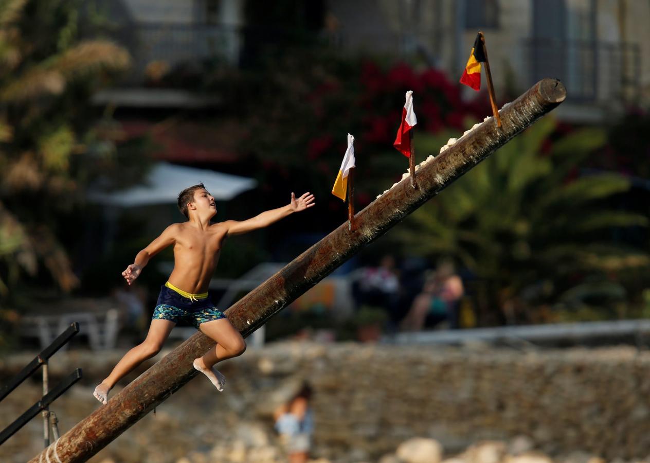 Un niño trata de agarrar una bandera en el "gostra", en un poste cubierto de grasa, durante la fiesta religiosa de San Julián, patrón de la localidad de San Julián, fuera de La Valetta, Malta.