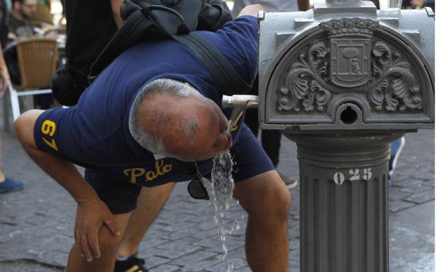 Un hombre bebe agua de una fuente en Madrid. 