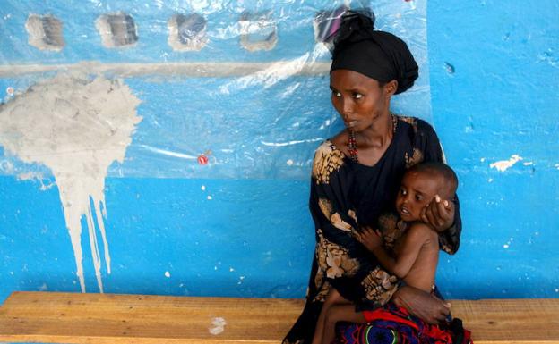 Una mujer somalí espera con su hijo en un centro de alimentación.