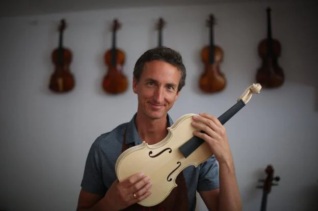 Marc Paquin posa con uno de sus últimos violines en el taller en el que trabaja como luthier, en Cájar.