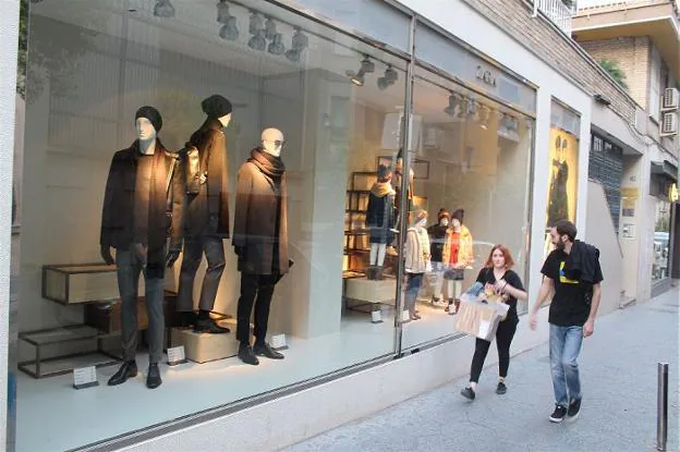 Dos jóvenes con manga corta pasan por delante de un escaparate con ropa de invierno ayer por la tarde en la capital.