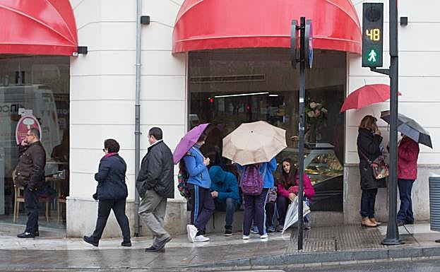 Escolares parapetados debajo del toldo de un comercio.