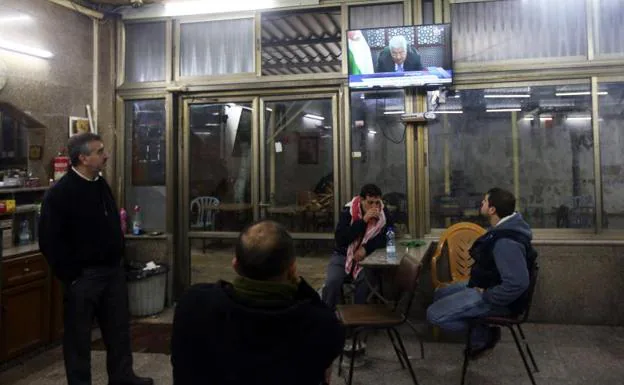 Palestinos siguen por televisión un discurso de Mahmud Abás.