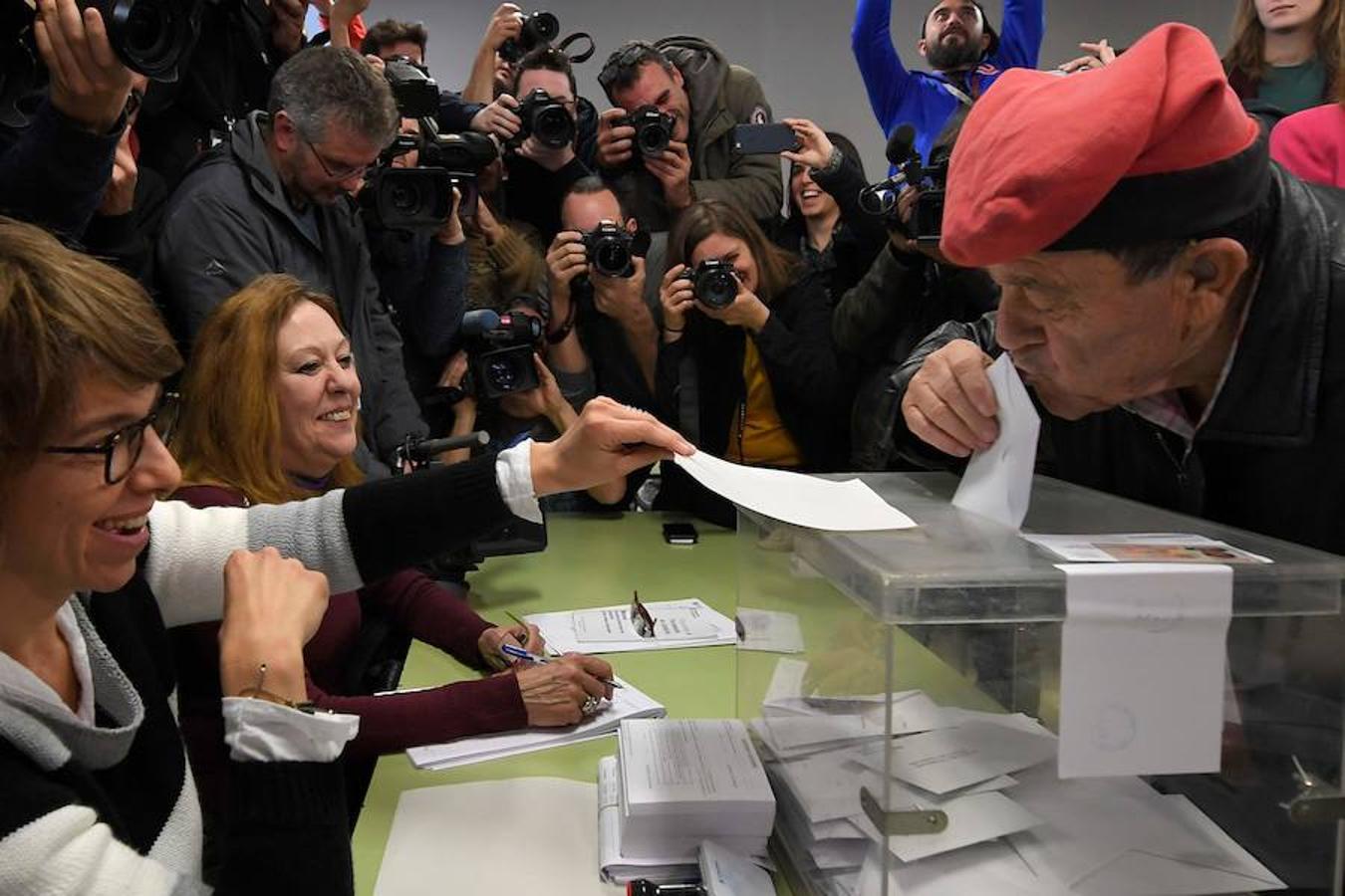 Un hombre con un sombrero barretina catalán besa su voto antes de introducirlo en la urna.