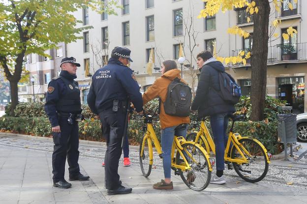 Una pareja de policías locales informa a dos ciclistas que circulaban por la Carrera de la Virgen, zona prohibida para bicicletas.