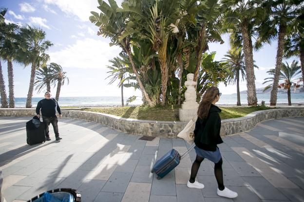 Dos turistas llevan sus maletas en Almuñécar.