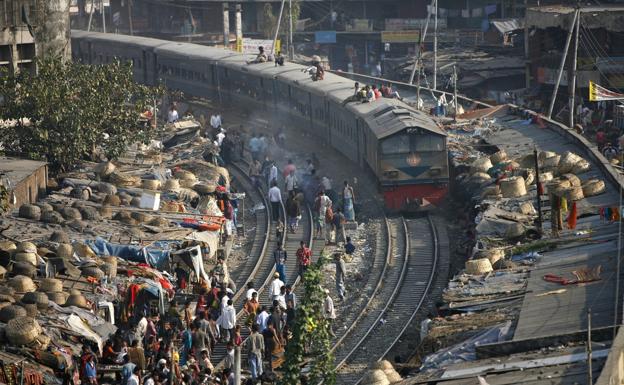 Un tren circula por la línea que cruza un improvisado asentamiento de chabolas, en Daca (Bangladés).