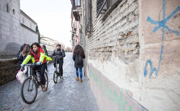 Ciclistas transitan cerca de la fachada del antiguo Convento Franciscano de los Ángeles, en la Carrera del Darro, cuya fachada presenta un pésimo estado.