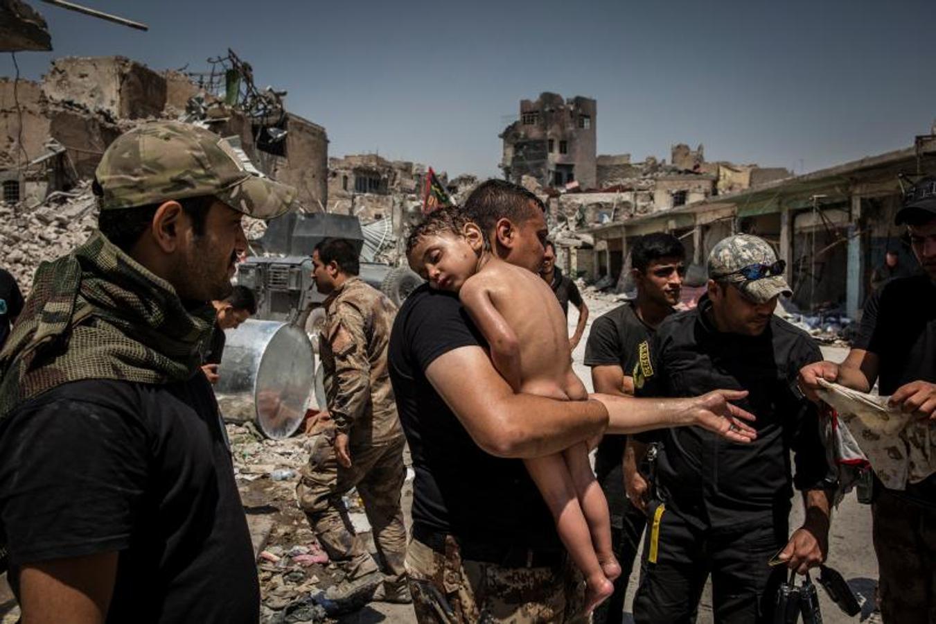 Un niño en brazos siendo evacuado de la última zona controlada por el Estado Islámico en la Ciudad Vieja de Mosul por un hombre sospechoso de ser militante, vigilado por soldados de las Fuerzas Especiales iraquíes, el 12 de julio de 2017