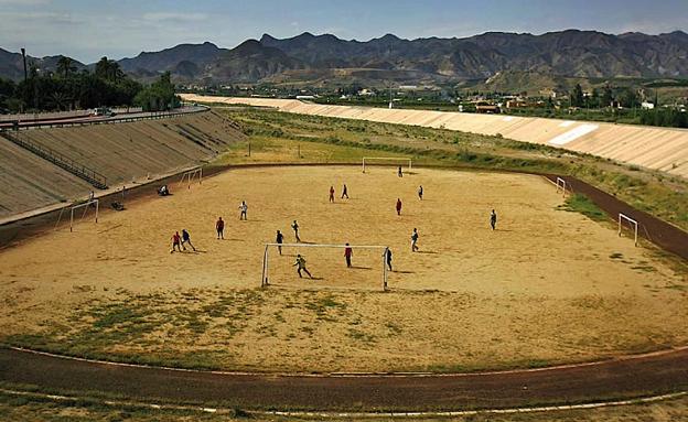 Jóvenes juegan al fútbol en el campo municipal sobre el cauce seco del río Almanzora en Cuevas del Almanzora.