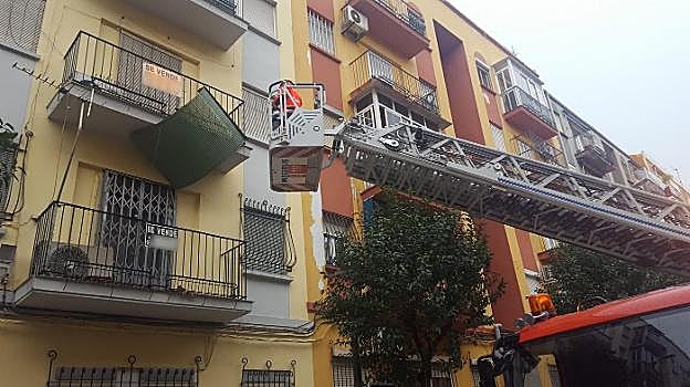 Los bomberos retiran una persiana a punto de caer en Jaén.