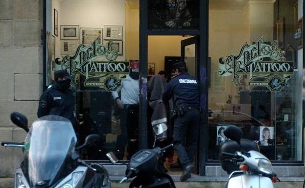 El tatuador es conducido por los agentes tras haber participado en el registro de su local.