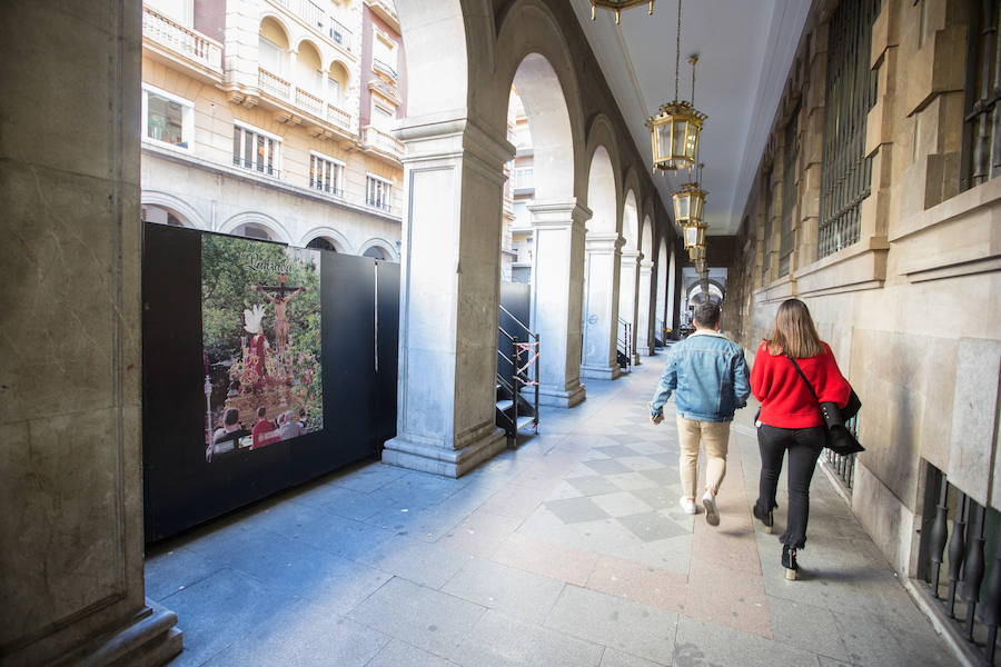 El Ayuntamiento inaugura una muestra de carteles con las fotos de Semana Santa de 2017 para embellecer la céntrica calle 'tapando' la parte trasera de las gradas de la carrera oficial.