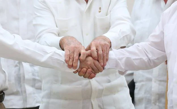 Raúl Castro sostiene las manos del presidente de Colombia, Juan Manuel Santos, y del líder de las FARC Rodrigo Londono. 