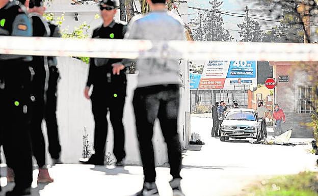 Los investigadores de la Guardia Civil inspeccionan el automóvil en el que fue acribillado el hombre, tras un cordón policial.