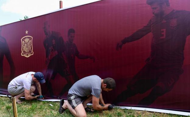 Operarios colocan un lienzo en el exterior del campo de entrenamiento de la selección en Krasnodar.