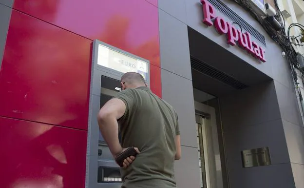 Un cliente saca dinero del cajero de una oficina del Banco Popular en Madrid. 