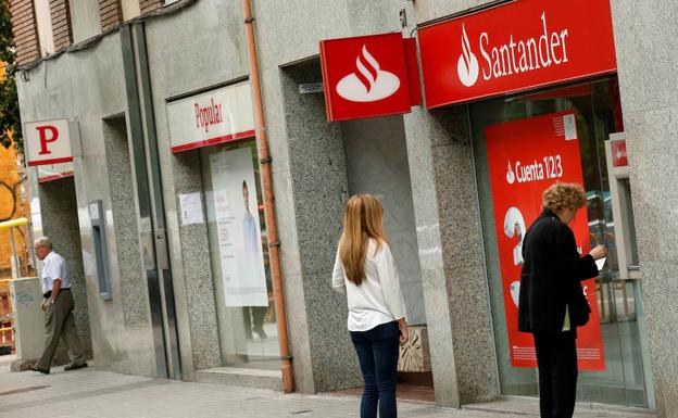 Una mujer saca dinero del cajero automático de una oficina del Banco Santander en Barcelona. 