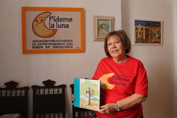 Marisol Escribano, presidenta de Pídeme la Luna, posa en la sede de la asociación junto con el cuento que les ayuda a financiarse.
