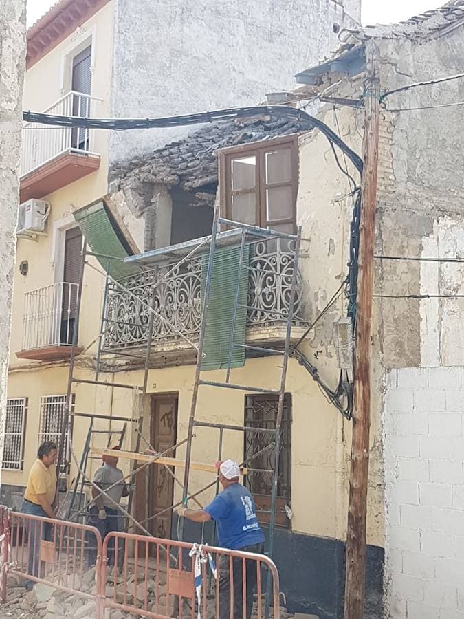 Unos trabajadores tienen que saltar del andamio en el que estaban retirando las tejas de un edificio al empezar a caerse la fachada