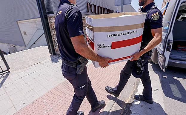 Agentes de la Policía nacional trasladan una caja con ropa para los inmigrantes que han estado custodiados esta semana en el polideportivo de Motril. 