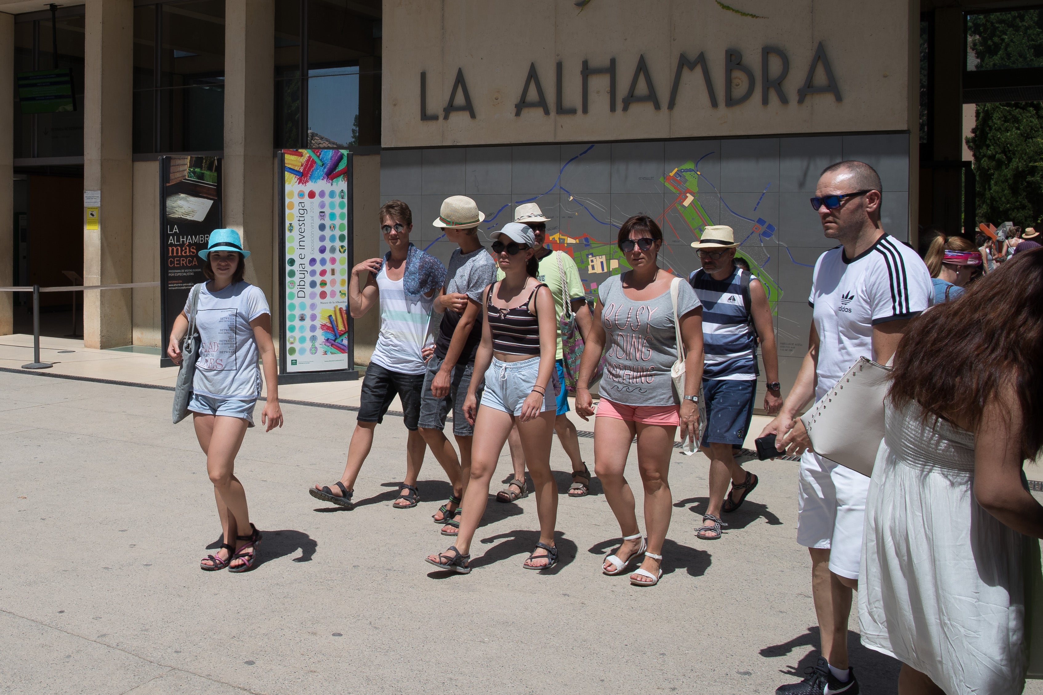 Un grupo de turistas extranjeros abandona la Alhambra junto al pabellón de acceso. 