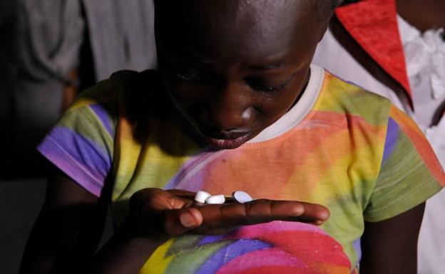 Un joven con VIH sostiene unas píldoras. 