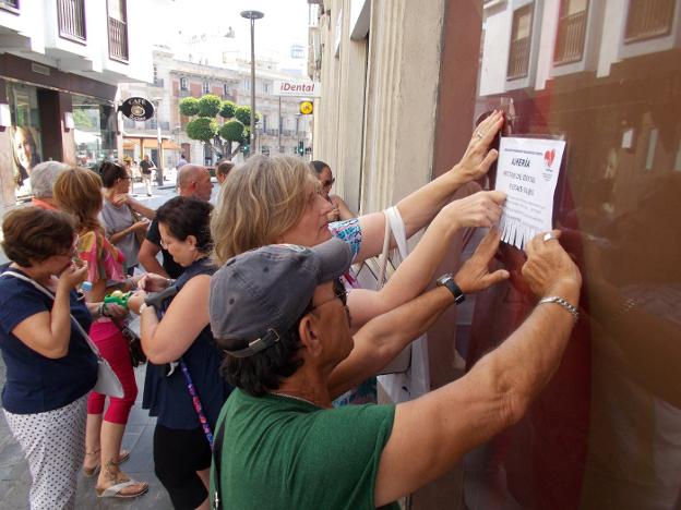 Un grupo de afectados de iDental de Almería coloca carteles en la clínica de calle Granada cerrada desde hace más de un mes. 