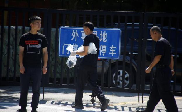 Personal de seguridad porta una bolsa de plástico con restos de la explosión frente a la embajada de EE UU en Beijing, China.