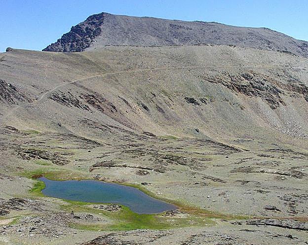 El Mulhacén muestra su arista oeste y la forma alomada hacia el sur. Imagen desde los crestones de Río Seco, con las laguna de Río Seco. 