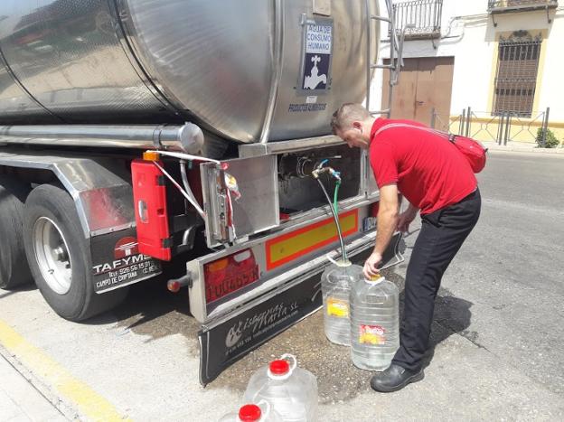 Un vecino de Navas de San Juan llena las garrafas de agua potable suministrada por el camión cisterna. 