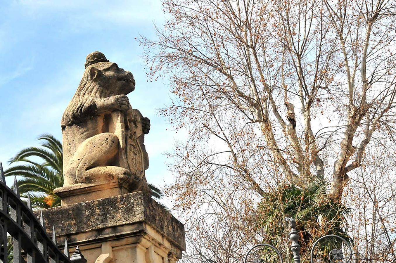Leones de terracota sobre las puertas del Salón en las Titas. Un paseo para conocer el 'bestiario' inanimado que habita en calles, puentes, jardines y plazas de Granada