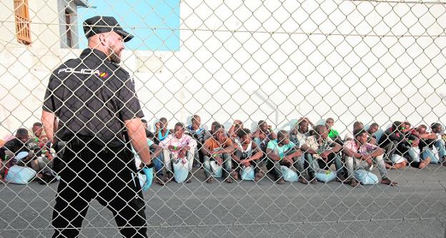 Un policía nacional custodia a los migrantes antes de ser reseñados.