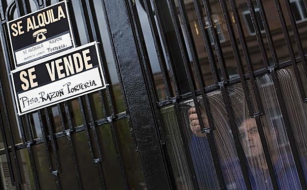 Carteles de «se alquila» y «se vende» cuelgan de la puerta de entrada de un edificio.