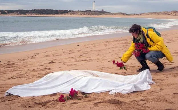 Una mujer deja flores junto a uno de los cadávere hallados en Caños de Meca. 