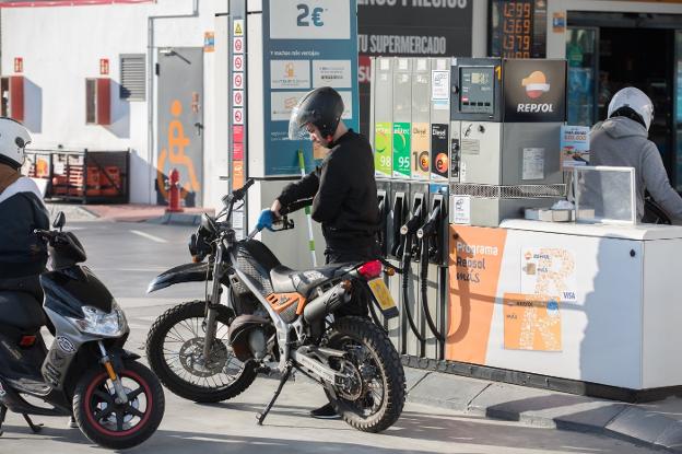Un usuario de una gasolinera se sirve el combustible en su ciclomotor.