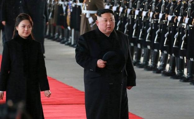 Kim Jong-un y su esposa, Ri Sol-ju, pasan revista a una guardia de honor durante su salida hacia China desde Pyongyang.