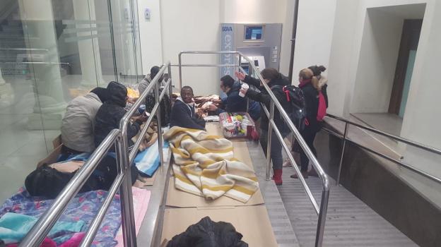 Voluntarios de Cáritas charlan con los inmigrantes que duermen en un cajero de la capital
