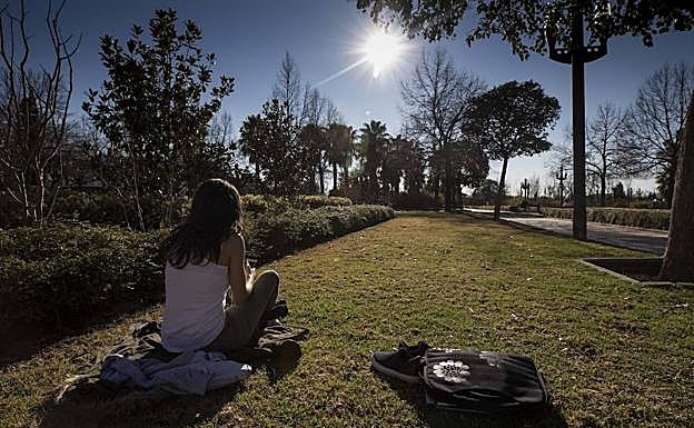 Una joven toma el sol en tirantes en el parque García Lorca de Granada.