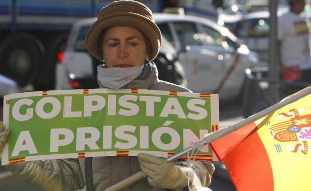 Una mujer sujeta un cartel y una bandera de España en las inmediaciones del Tribunal Supremo, donde hoy empieza el juicio del 'procés'.