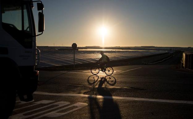 Un trabajador del campo circula con su bicicleta entre invernaderos. 