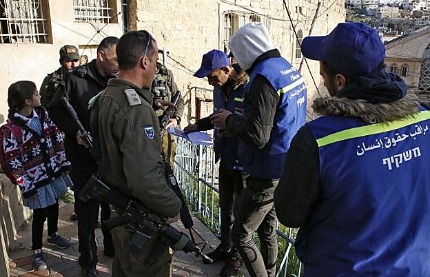 Soldados israelíes piden documentación a los 'chalecos azules' palestinos que quieren llenar el vacío dejado por los observadores internacionales expulsados.