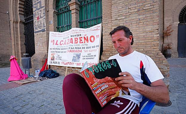 Alcazabeño, que lleva ocho días en huelga de hambre, lee una revista taurina ante las puertas del coso granadino.