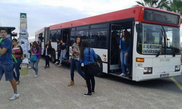 Jóvenes universitarios se bajan del autobús en el campus. 