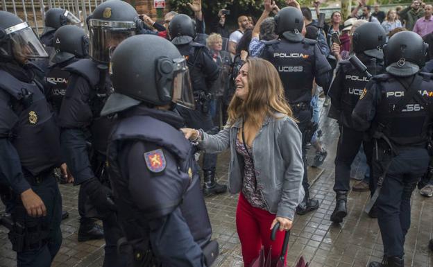 Una joven llorando ante un agente en el exterior del Instituto Can Vilumara de Hospitalet de Llobregat el 1-O.