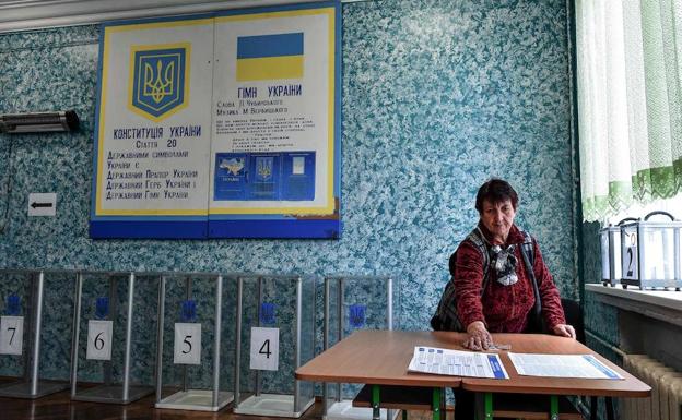 Una mujer limpia la mesa de un colegio electoral en Kiev.
