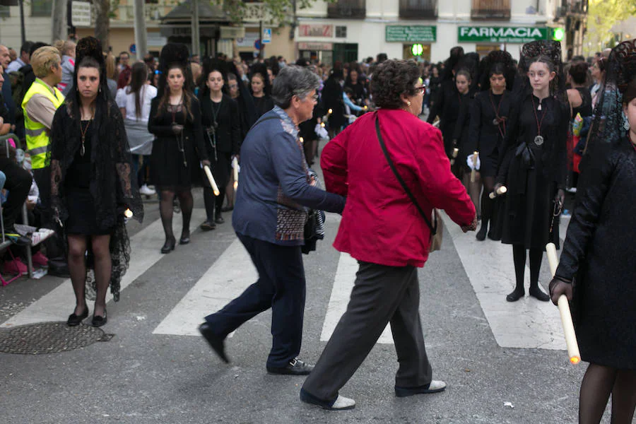 Dos mujeres cruzan por un paso de peatones en mitad de un cortejo de mantillas en Plaza Mariana Pineda.