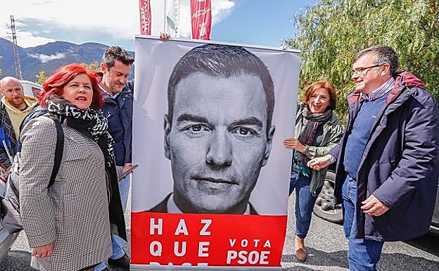 Los candidatos, un momentazo, se fotografían junto a la foto electoral del líder. 