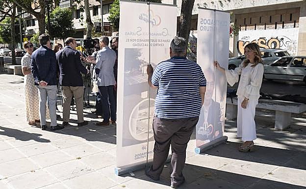 Eva Martín y un colaborador de la campaña popular sostienen los 'roll up' de la presentación. 