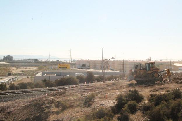 Máquina excavadora iniciando los trabajos junto a las vías de ferrocarril en su discurrir por el barrio de El Puche.